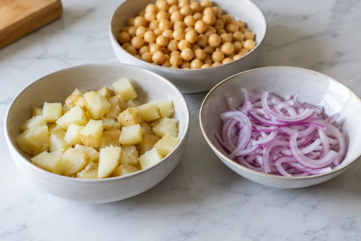 Bowls of diced potato, chickpeas and sliced red onion