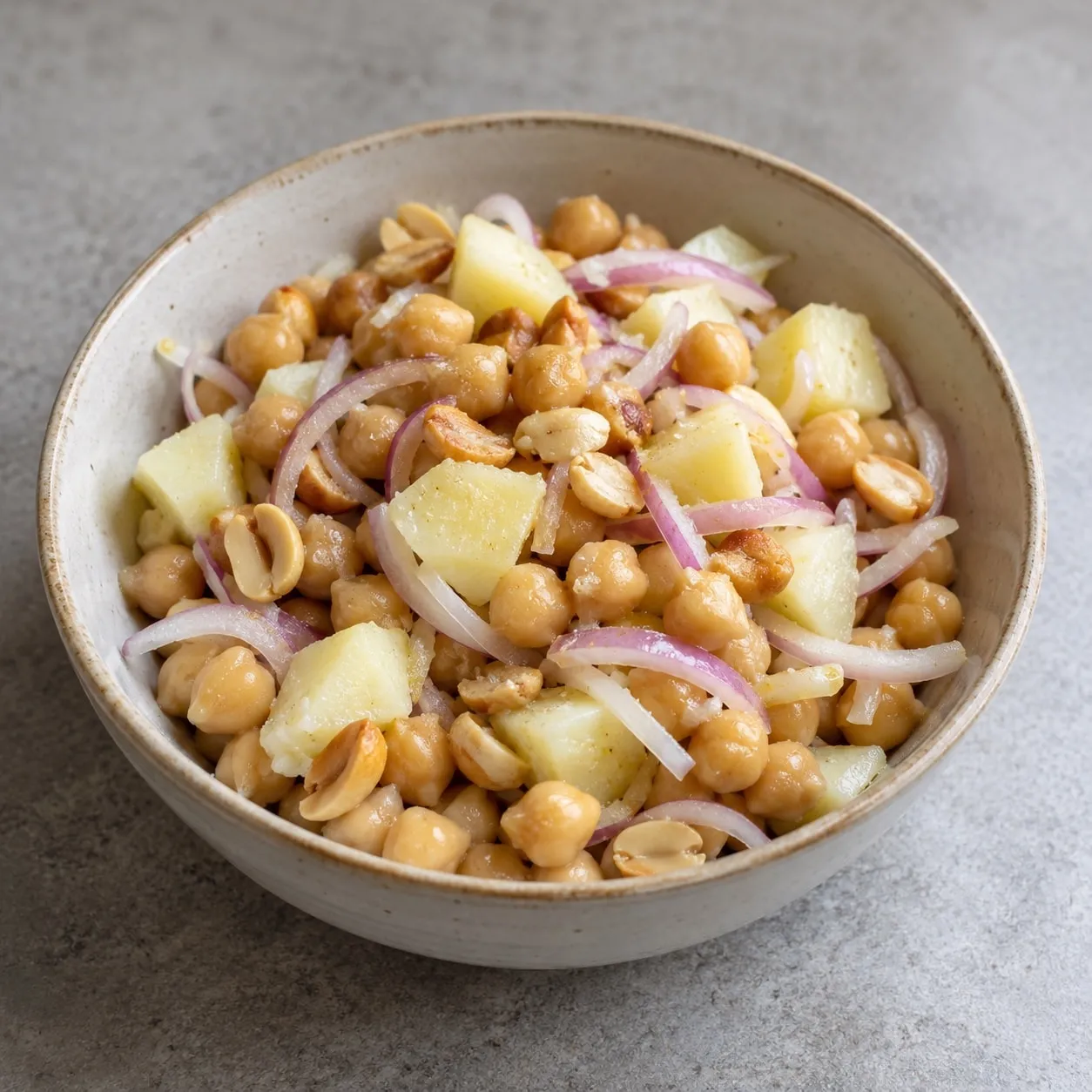 Chickpea salad with diced potato, red onion and peanuts in a bowl